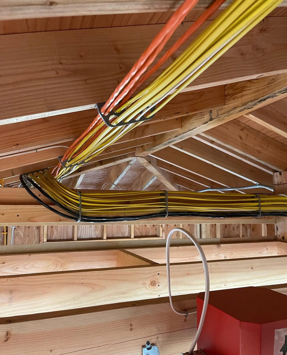 Organized bundles of home-run cables across ceiling framing